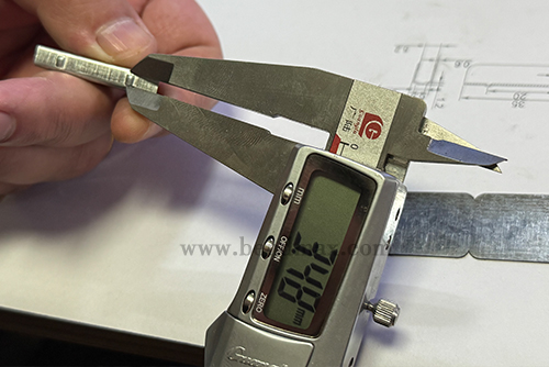 Digital caliper measuring a critical dimension of a custom metal part-3