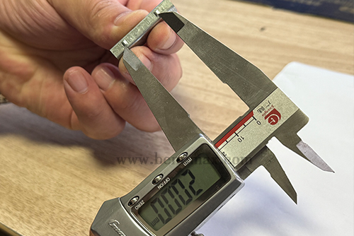 Digital caliper measuring a critical dimension of a custom metal part-2